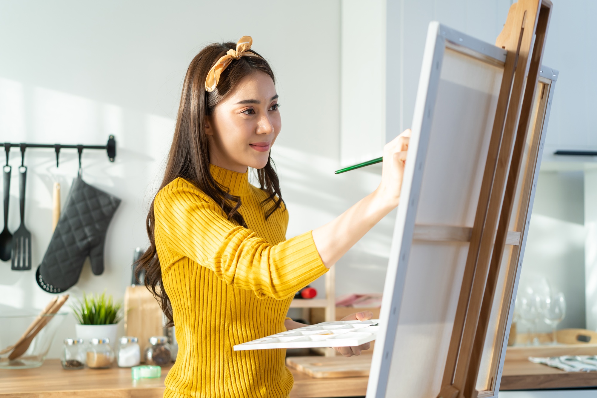 Asian young talented woman artist coloring on painting board in house.